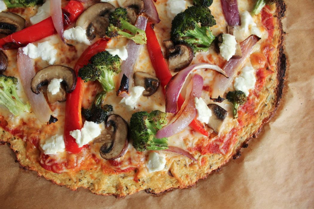 Unsliced cauliflower crust pizza with roasted vegetables and goat cheese.
